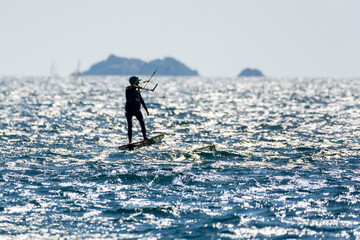 Fototapeta na wymiar Hyeres, Almanarre beach, France, July 10, 2021. Extreem water sport - wing foil, kite surfing, wind surfindg, windy day on Almanarre beach near Toulon, South of France