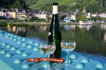 White quality riesling wine served on old bridge across Mosel river with view on old German town in...