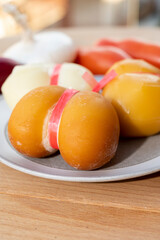 Cheese collection, variety of Italian cow milk cheese scamorza with Italian houses on background