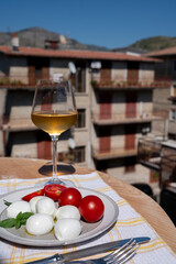 Cheese collection, white balls of Italian soft cheese mozzarella served with fresh tomatoes and basil and white wine