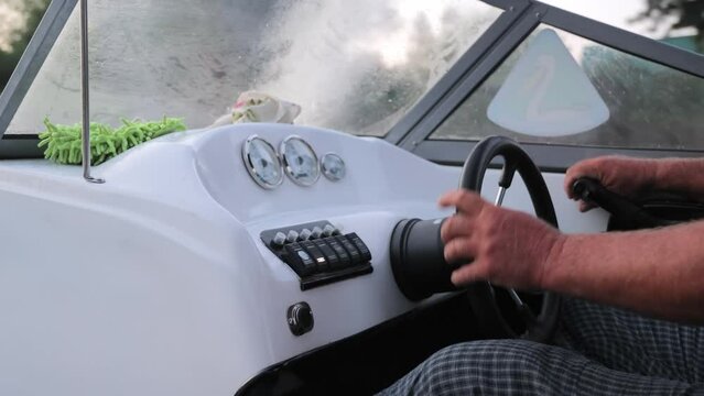 A man controls the helm of a speedboat. Hands at the helm of the boat.