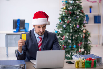 Young male employee celebrating Christmas at workplace