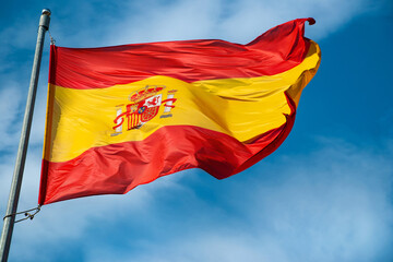 Flag of Spain waving in the wind on the sky with clouds