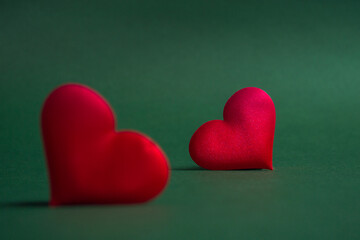 Composition for Valentine's Day. On a green background, red hearts closeup with copy space