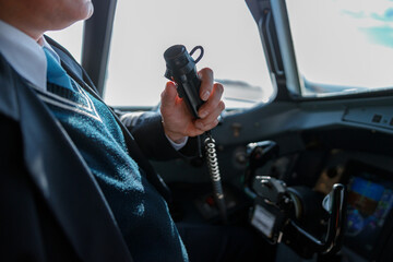 Male pilot using aircraft radio microphone in cockpit - obrazy, fototapety, plakaty