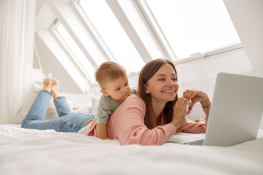 Prettyy lady using laptop while spending time with her baby at home