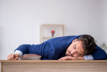 Young male employee extremely tired in the office