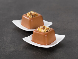 Vegan Chocolate walnut cream pudding in the shape of a small square savarin on a plate on a dark gray background