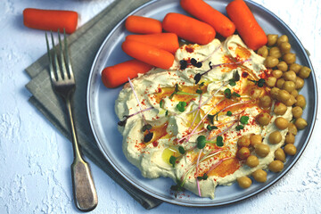 Hummus with olive oil and baby carrots on a plate.