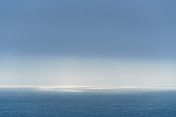 sunlight is reflected in the sea, blue waves and bright light against the sky, view to the horizon