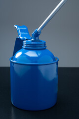 Closeup of blue retro oil gun against dark background.