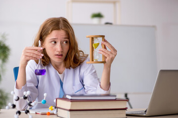 Young female chemist student in time management concept