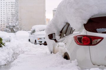Snowfall in the city. Car covered in several inches of snow. Car almost totally buried