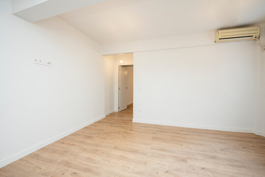Empty living room with plain white paint walls and light wood flooring