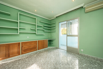 Residential living room with plain green painted walls and plaster and wood shelving