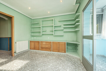 Residential living room with plain green painted walls, plaster and wood shelving and sky blue deck
