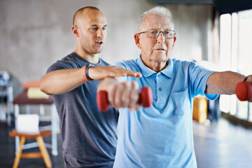 Rehabilitation is never easy. Shot of a physiotherapist helping a senior man with weights. - obrazy, fototapety, plakaty