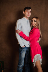 A girl in a beautiful pink dress hugs a man in a shirt and trousers