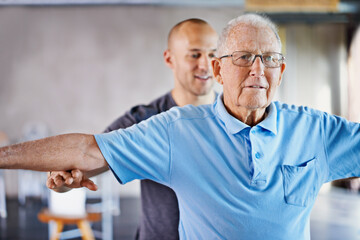 It's so important to stretch. A trainer helping an elderly man with fitness.