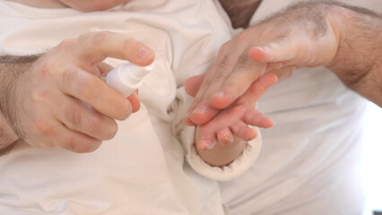 父親が赤ちゃんの手にスプレーをかけるイメージ