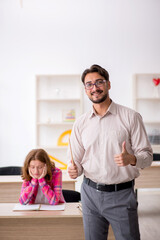 Young male teacher and redhead girl in the classroom