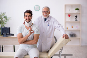 Fototapeta premium Young neck injured male patient visiting old male doctor