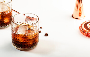 Black russian cocktail, alcohol drink with vodka, coffee liqueur and ice, white table background, bar tools, copy space