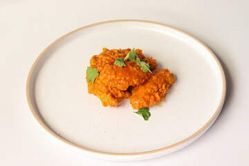 spicy buffalo wing on a plate served gourmet decorated with coriander leaves
