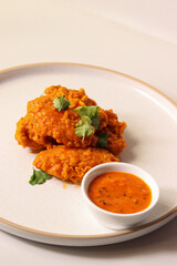 spicy buffalo wing on a plate served gourmet decorated with coriander leaves