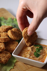 woman's hand holding a chicken nuggets at lunch, with ketchup and spicy buffalo sauce