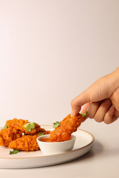 White Woman Holding Buffalo Wing In Her Hand And Filling It With Red Hot Sauce