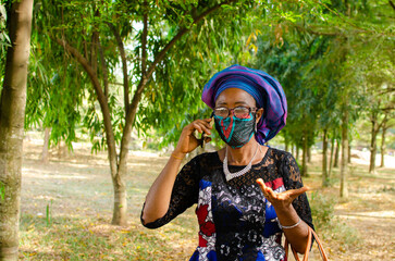 african woman wearing face mask to the prevent herself from the outbreak from the society while...