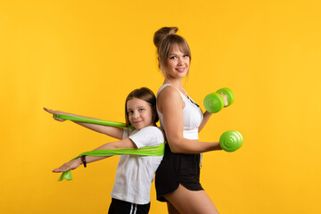 Healthy fit mom and daughter wearing sport wear in studio using resistive exercise band and...