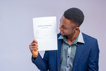 handsome man african doctor looking at the covid vaccination on form in his hand