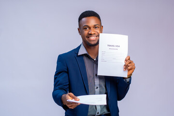 handsome young travel agent smiling as he holds visa application form