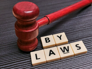 Word bylaws made from square letter tiles with gavel against black background.