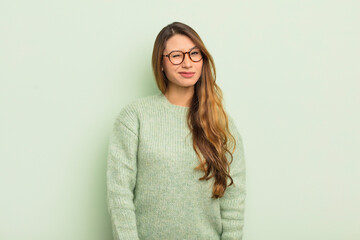 asian woman looking happy and friendly, smiling and winking an eye at you with a positive attitude
