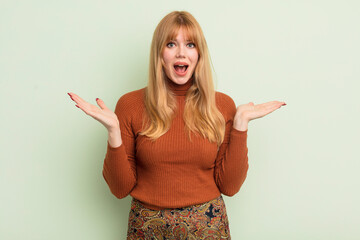 redhead pretty woman feeling happy, excited, surprised or shocked, smiling and astonished at...