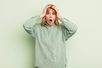 redhead pretty woman feeling horrified and shocked, raising hands to head and panicking at a mistake