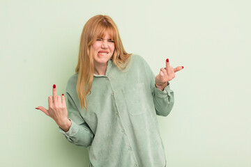 redhead pretty woman feeling provocative, aggressive and obscene, flipping the middle finger, with...