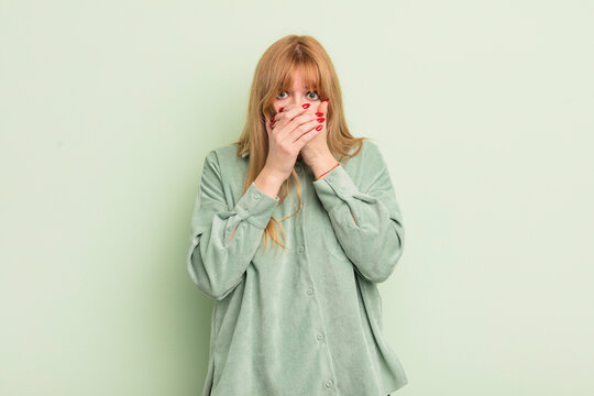 redhead pretty woman covering mouth with hands with a shocked, surprised expression, keeping a secret or saying oops