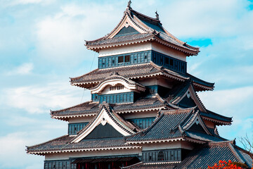View of Matsumoto castle with blue skies and tree on right in Japan