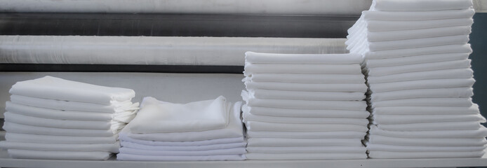 Folded white sheets or fabrics in an industrial laundry.
