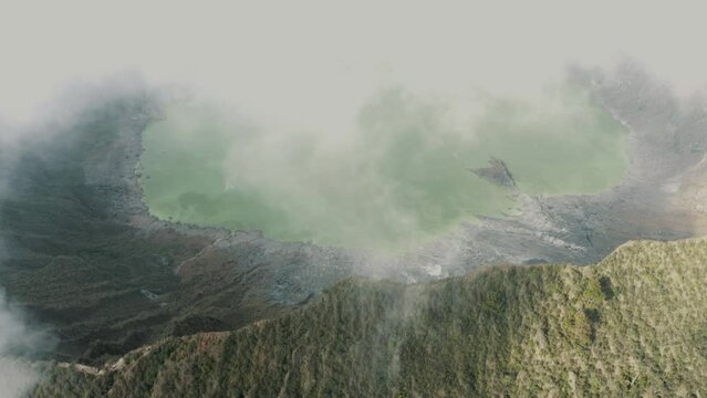 Beautiful aerial drone shot of white clouds passing over the crater and lake of El Chichonal volcano in Chiapas, Mexico on a cloudy day.