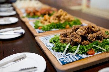 Party food, fried chicken, sausages, bacon rolls and sandwiched on buffet table. Soft focus image.