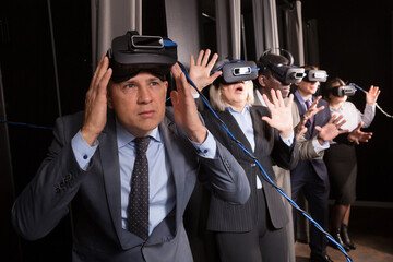 Portrait of man and his colleagues wearing virtual reality glasses in entertainment room