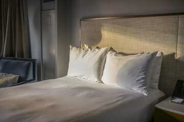 Empty bed with white pillows in hotel room