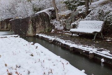 雪の積もった公園内の庭園のベンチ