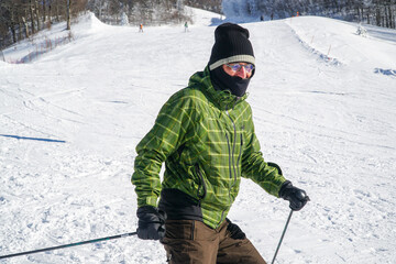 Middle aged man skiing downhill happily. Middle aged man in warm clothes posing while skiing....