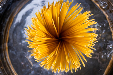 Abstract background with selective focus on spaghetti in boiling water pans. Bunch of spaghetti in boiling water. - obrazy, fototapety, plakaty